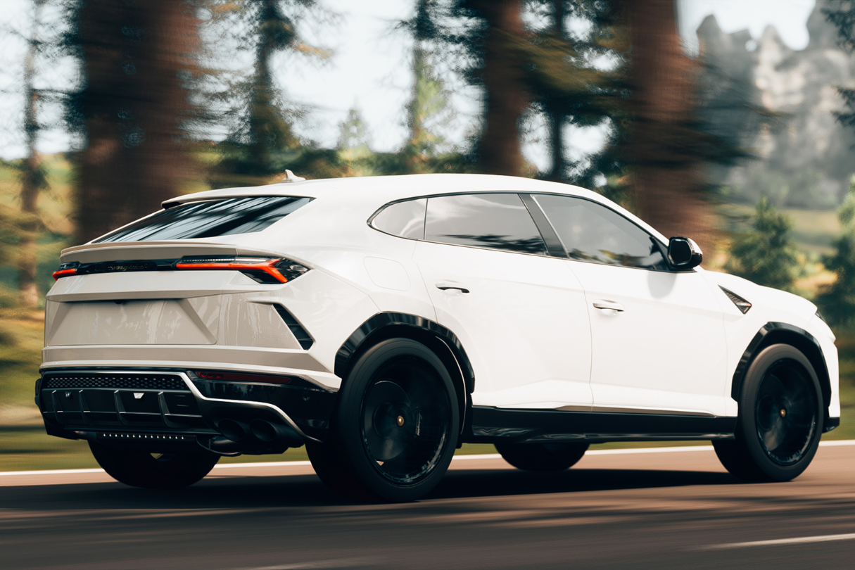 A white lamborghini urus is driving down a road next to trees.