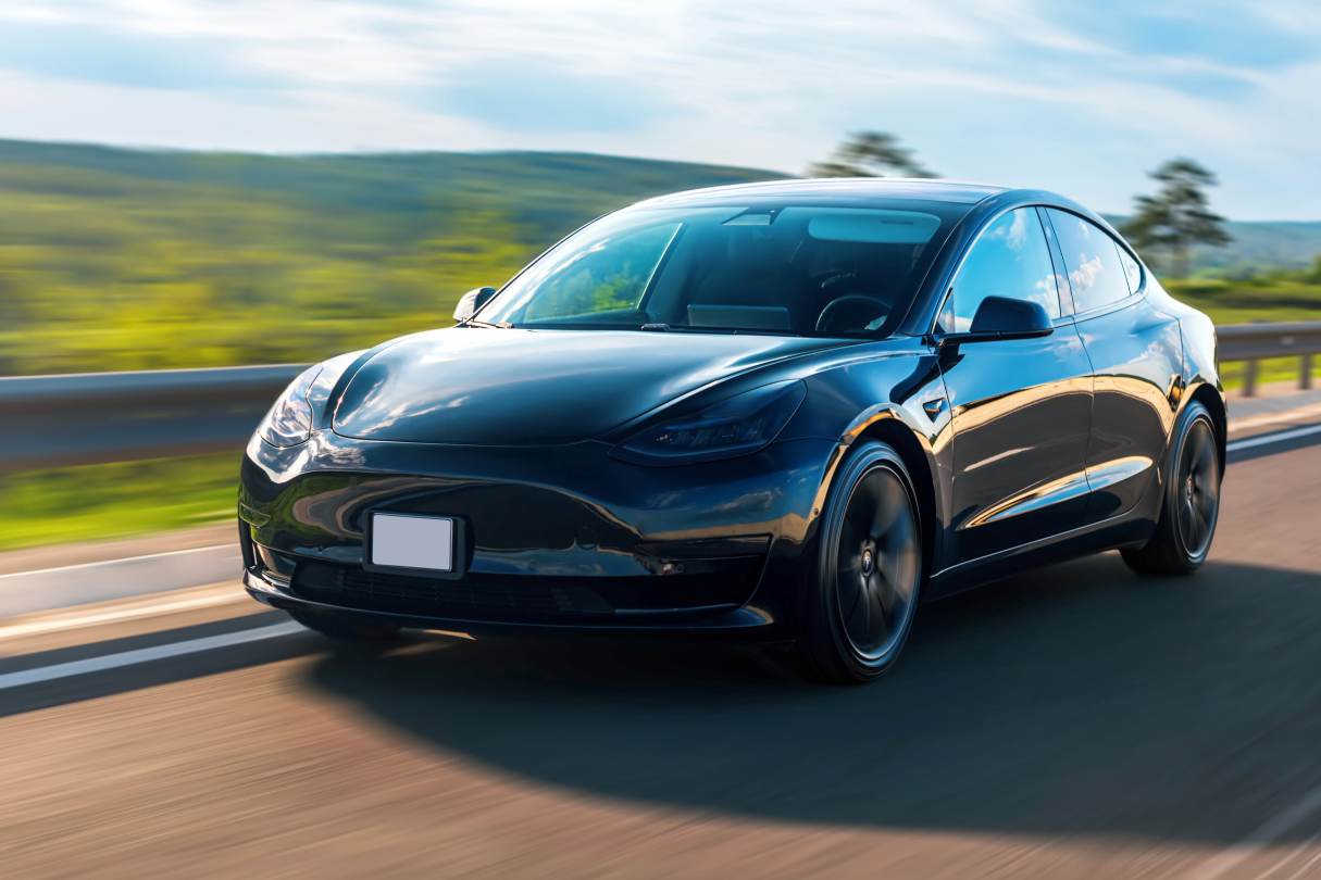 A black tesla model 3 is driving down a highway.