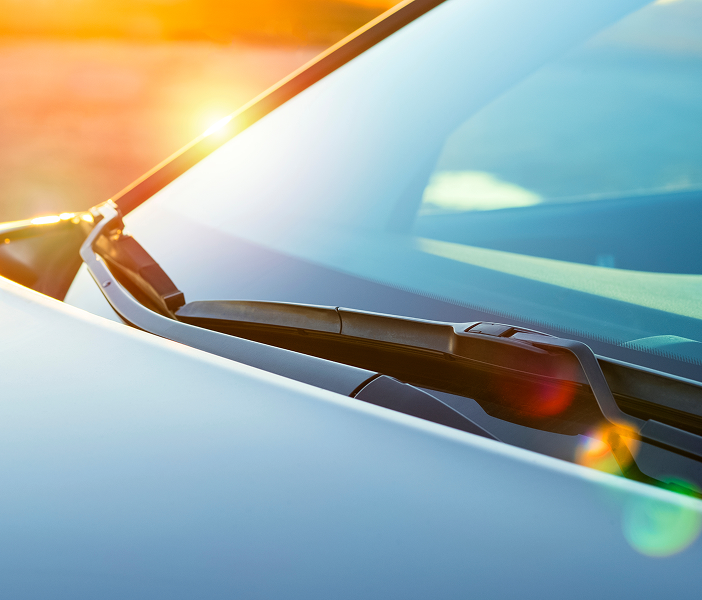A man in a hooded jacket is breaking into a car.