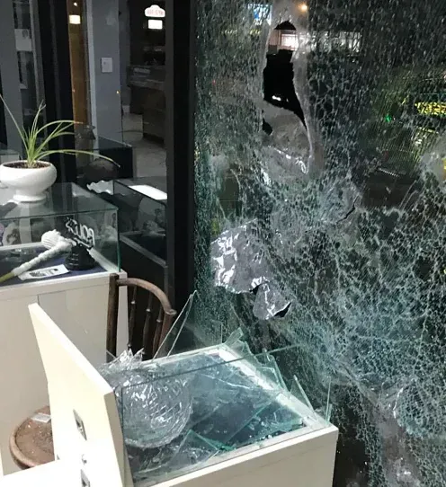 A broken glass window with a display case in front of it