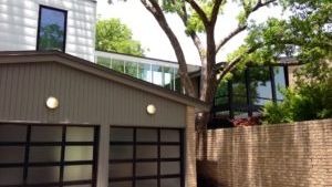 A house with two garage doors and a tree in front of it.