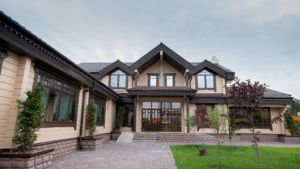 A large house with a lot of windows is sitting on top of a lush green lawn.