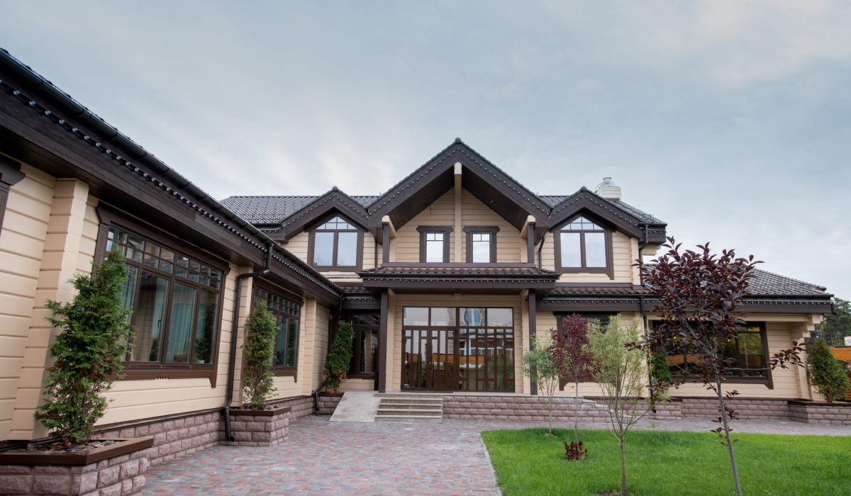 A large house with a lot of windows and a brick driveway in front of it.