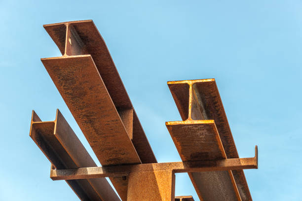 A bunch of rusty metal beams stacked on top of each other against a blue sky.