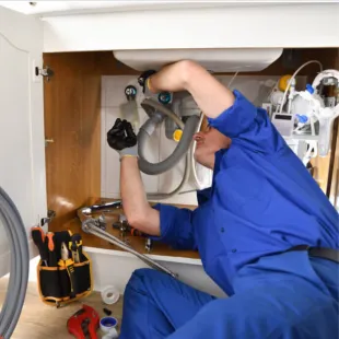 Doctor Cool - A man in a blue shirt is working under a sink