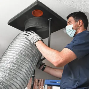 Doctor Cool - A man wearing a mask and gloves is working on a duct.
