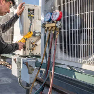 Doctor Cool - A man is working on an air conditioner with a pair of pliers