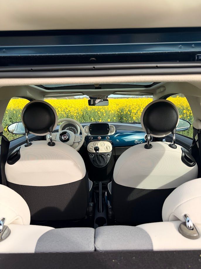 Interieur van een cabriolet, gezien vanaf de achterbank met de kap open en de voorstoelen zichtbaar.