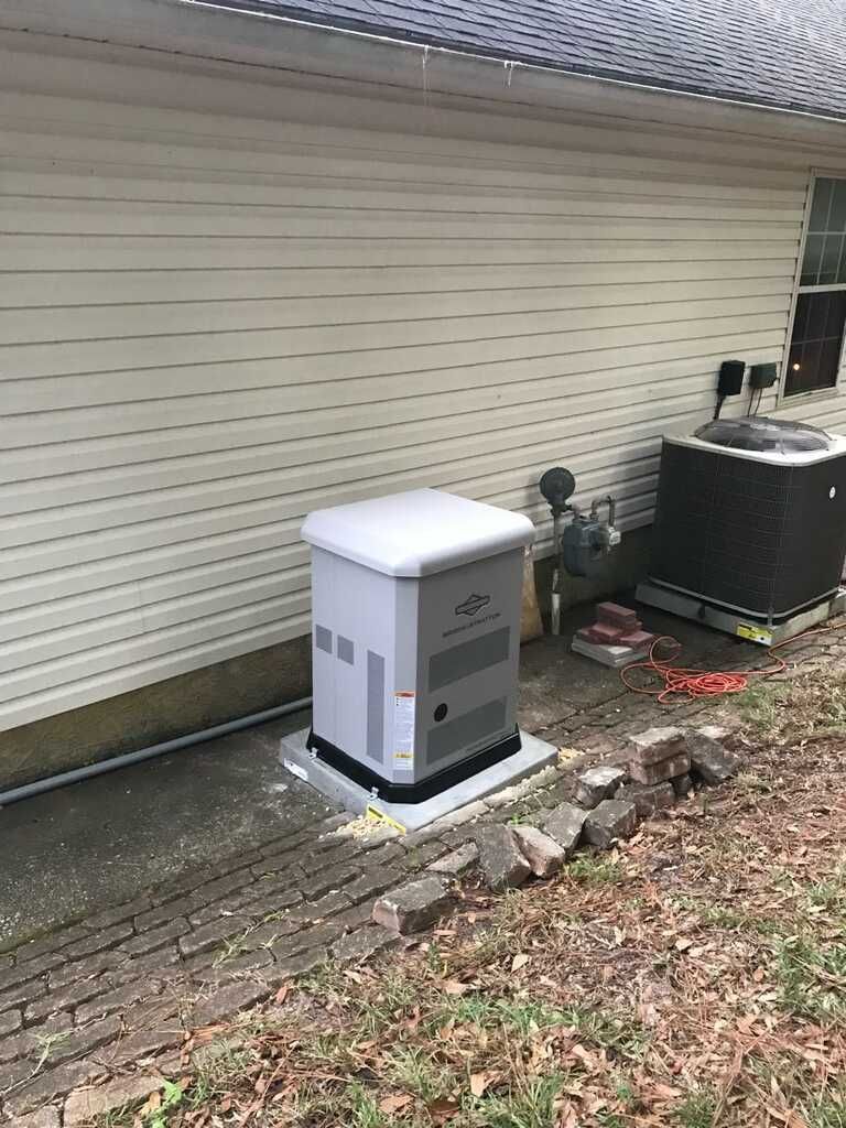 A generator is sitting on the side of a house.