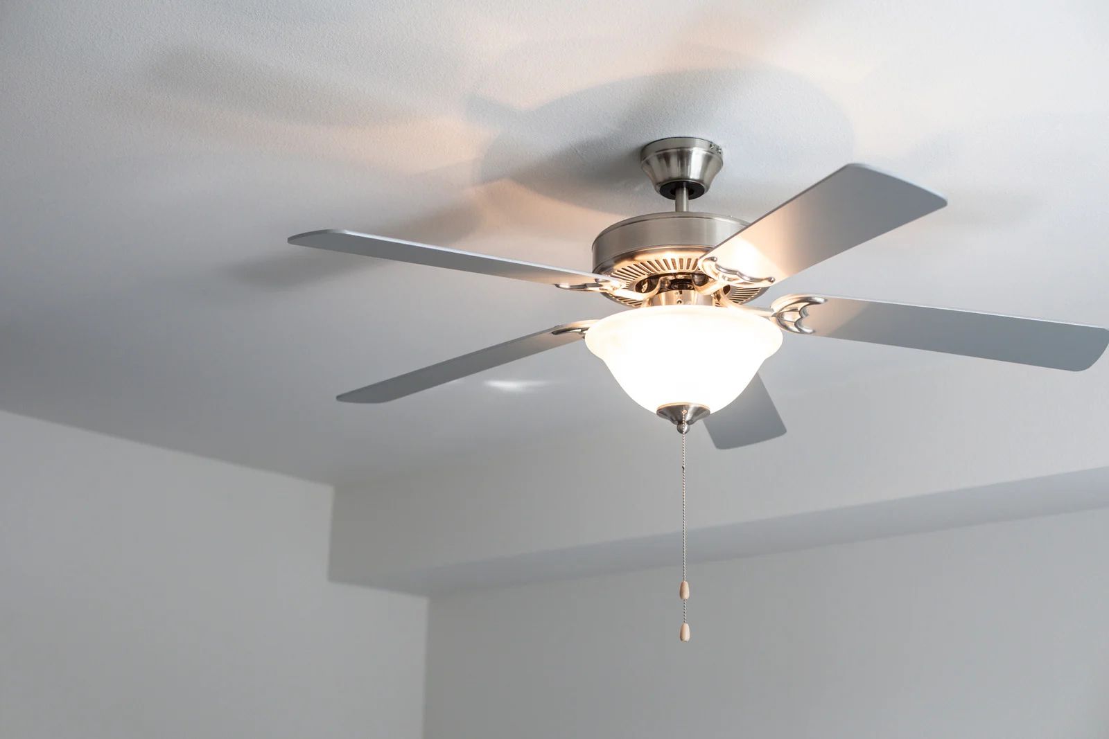 Ceiling fan with five silver blades and a frosted glass light fixture.