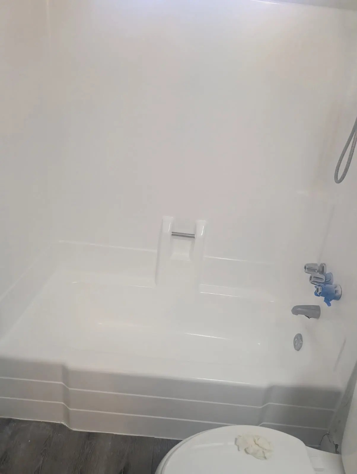Empty white bathtub with built-in seat and blue faucet handles in a bathroom