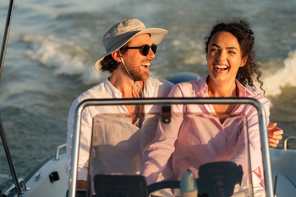 A smiling couple on a boat, laughing as they enjoy the ride on the water.