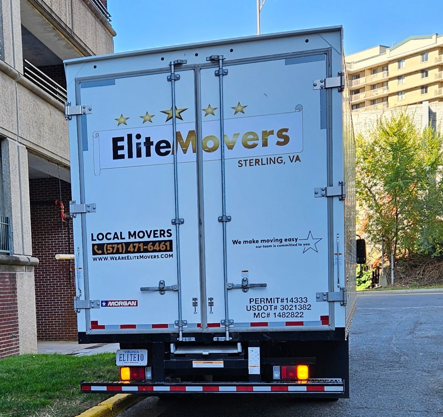 A white item movers truck is parked in front of a building