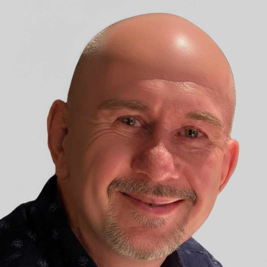 Bald man with a slight smile, wearing a dark blue shirt; gray background.