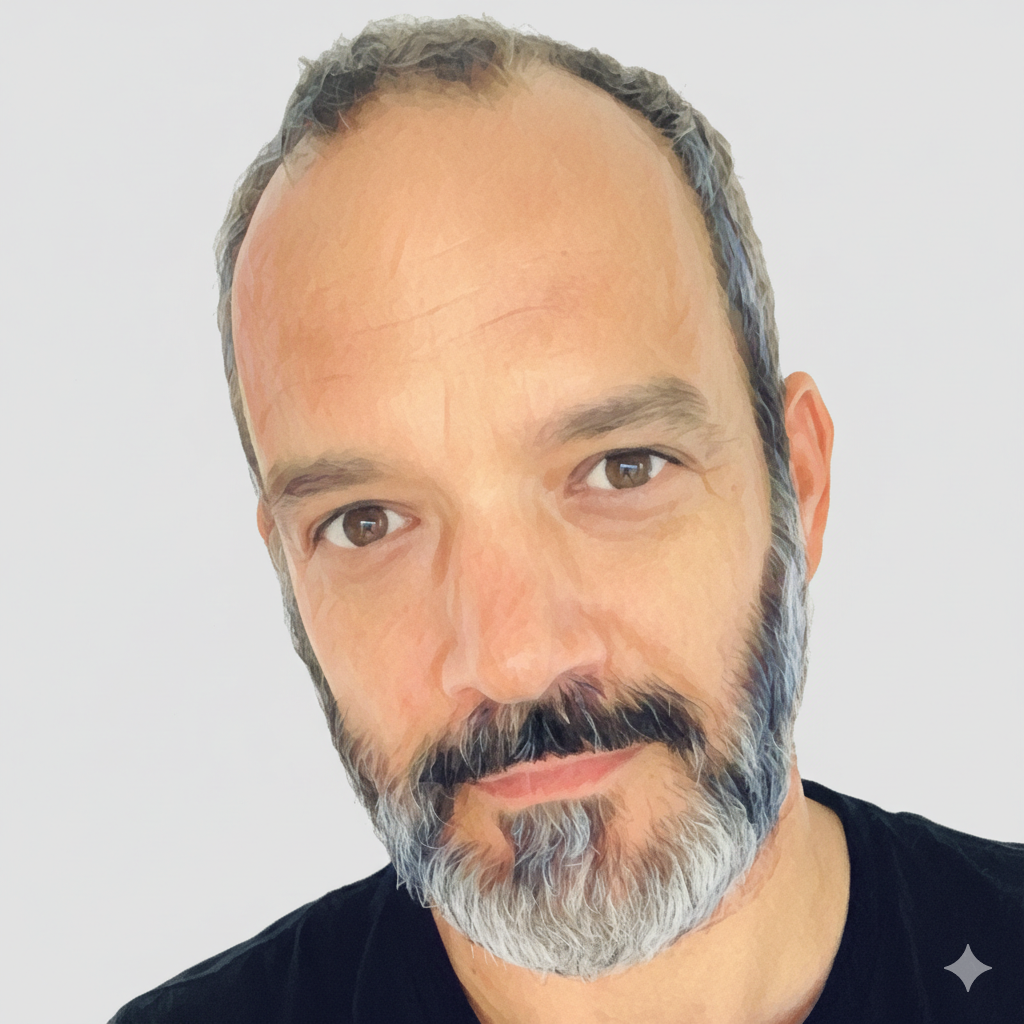 A man with a beard and brown eyes, looking directly at the viewer. He wears a black shirt against a white background.