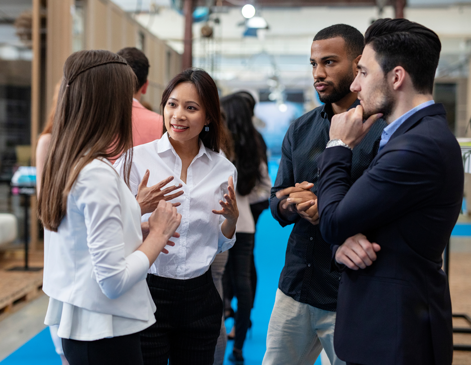 Group of diverse professionals engaged in conversation at an indoor event, focused on collaboration.