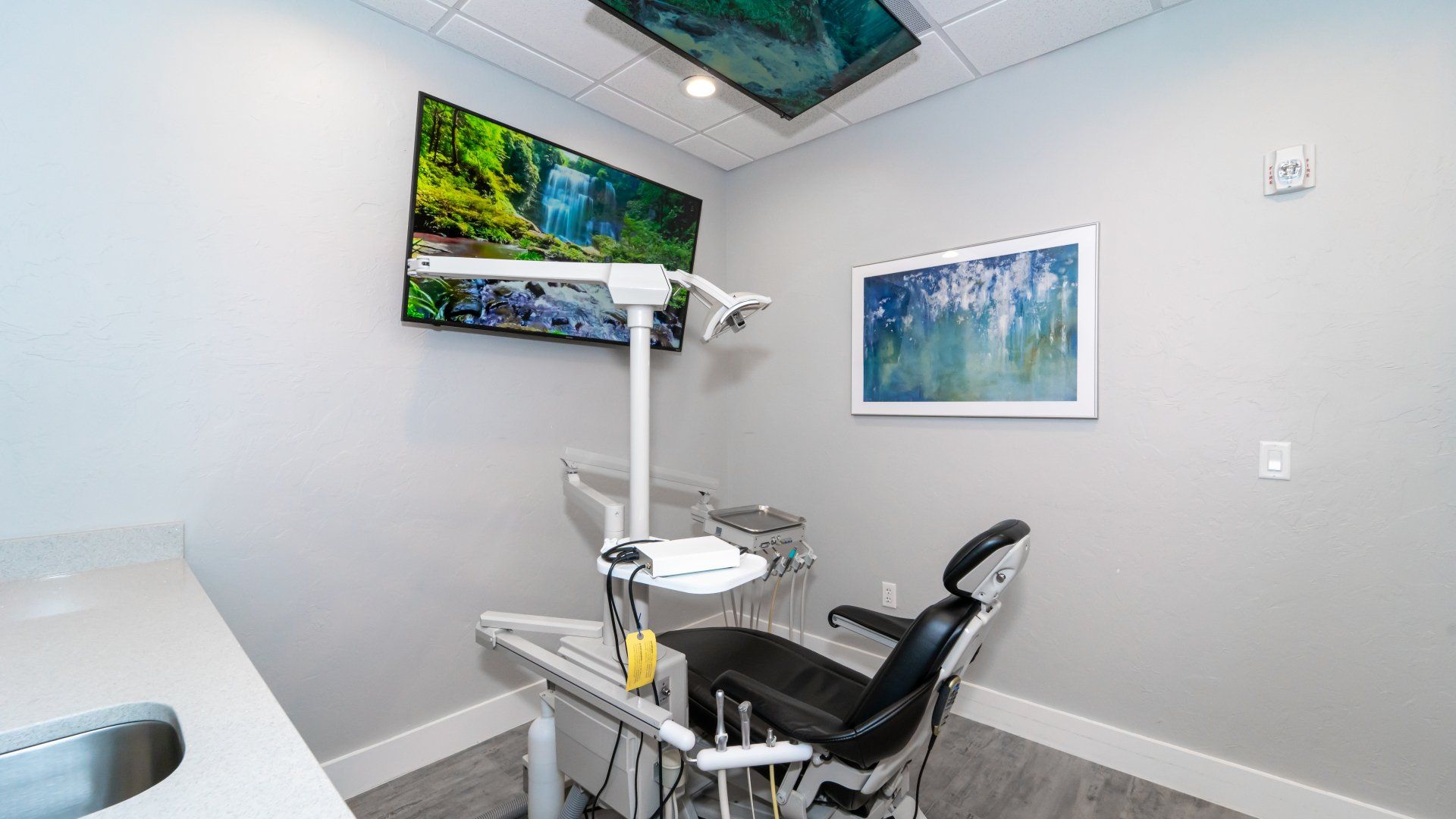 A dental office with a dental chair and a sink.