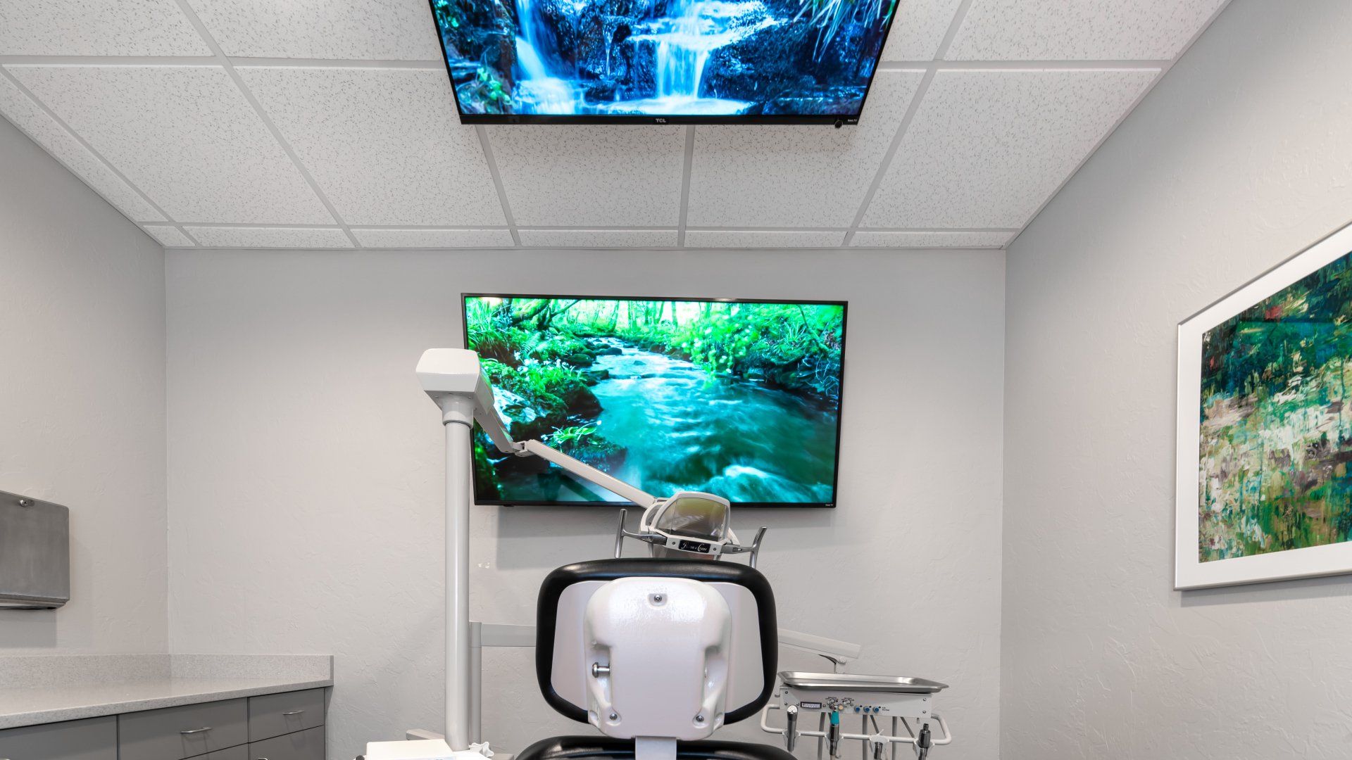 A dental office with a dental chair and a television on the wall.