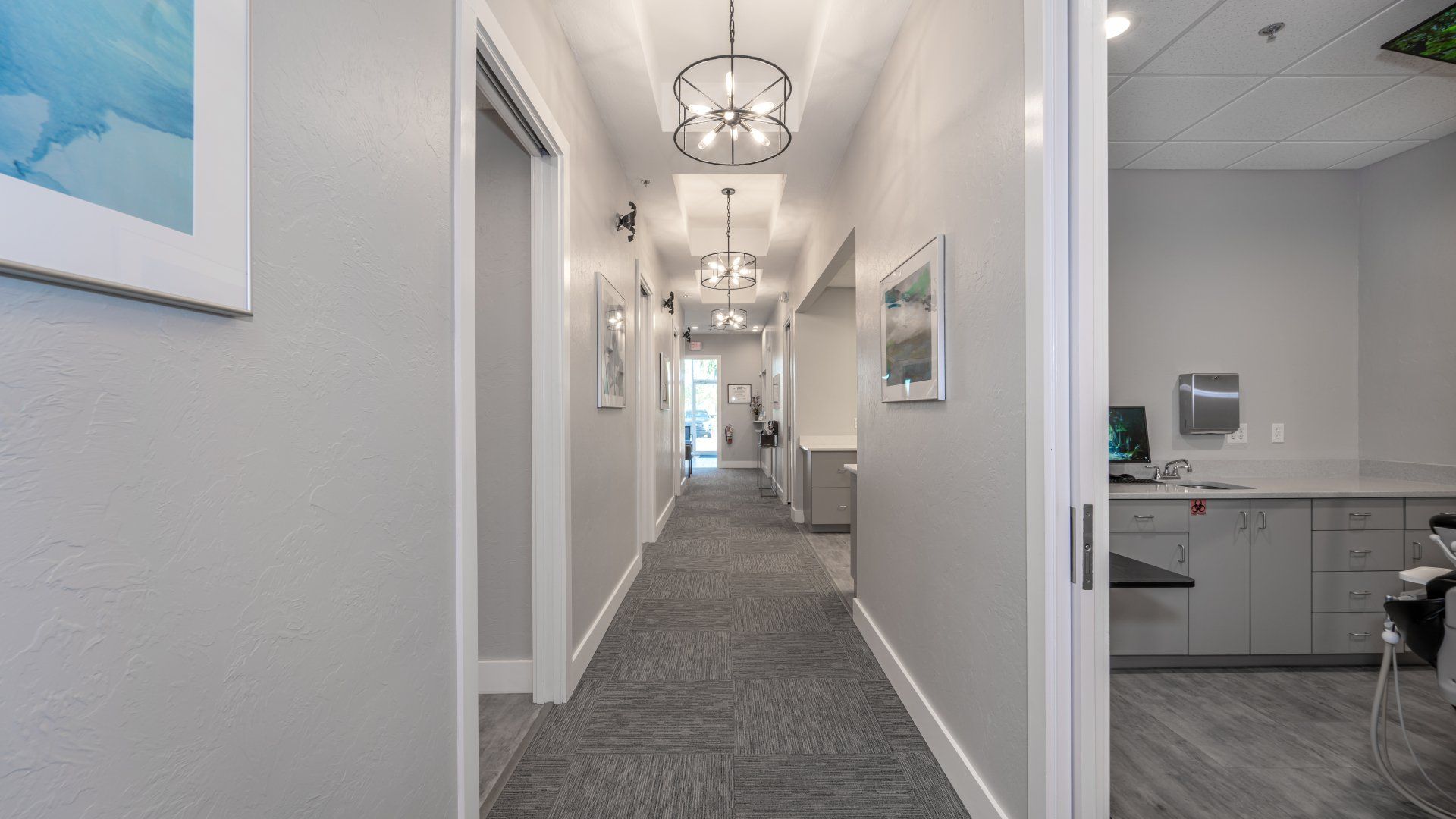 A long hallway in a dental office with a chandelier hanging from the ceiling.