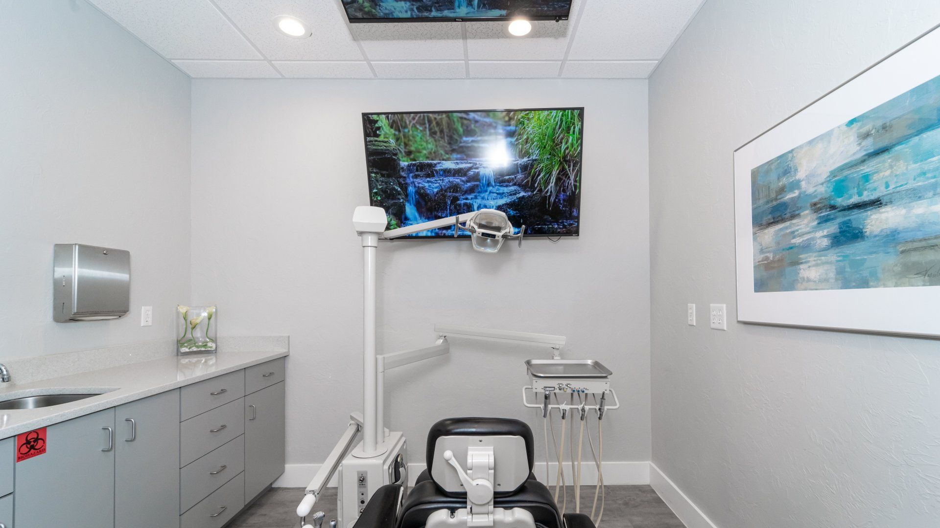 A dental office with a large television on the wall above the dental chair.