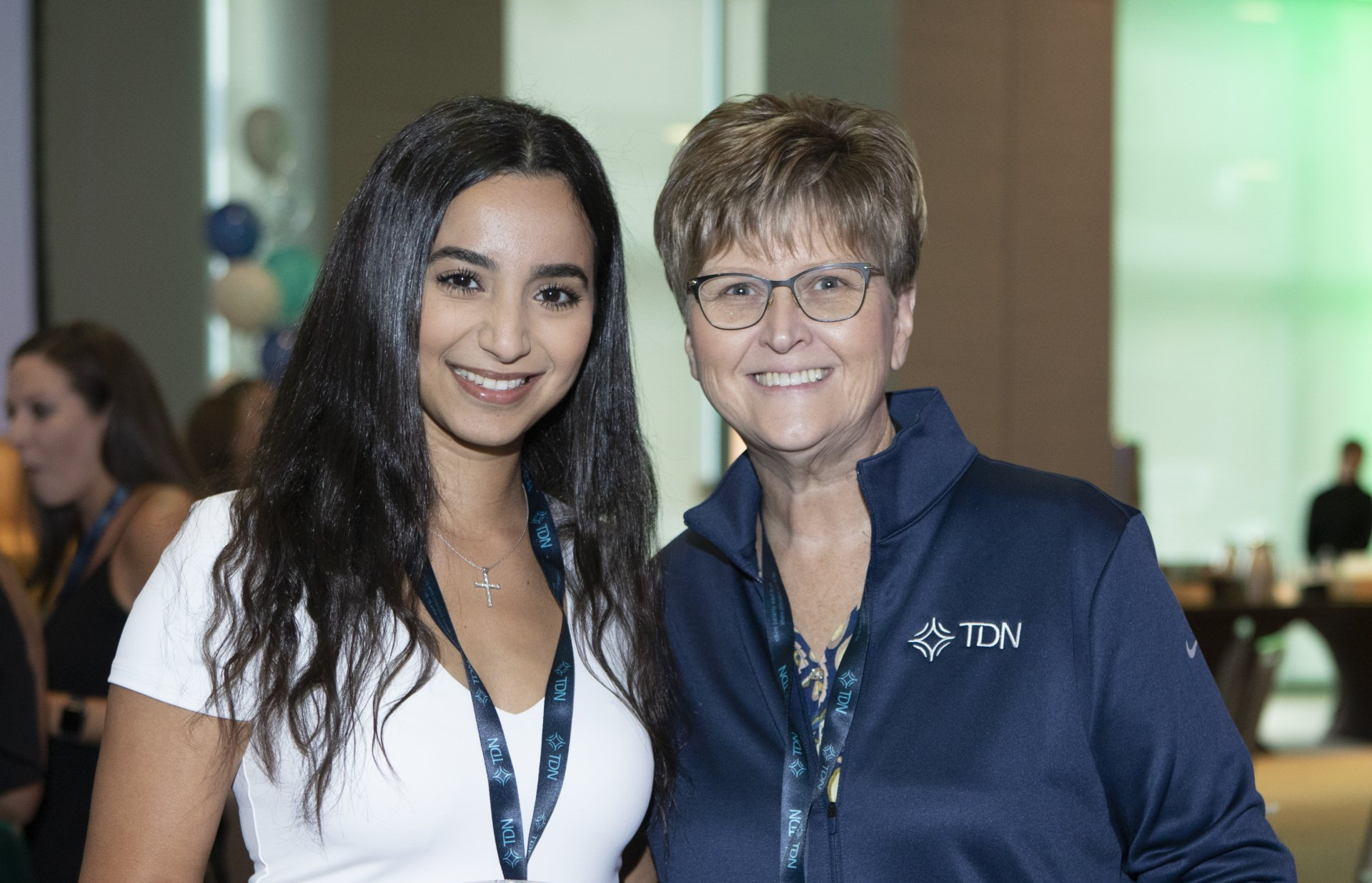 Two women are posing for a picture together in a room.