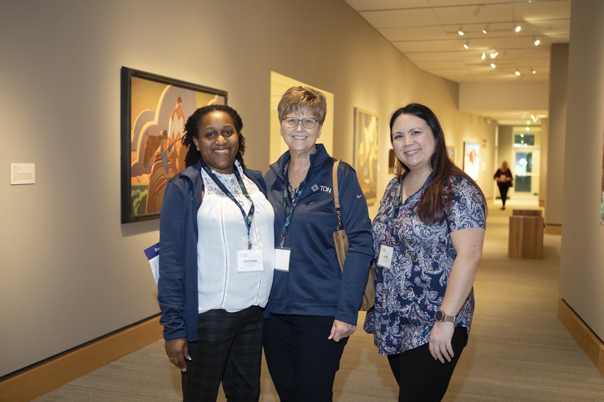 Three women are posing for a picture in a museum hallway.