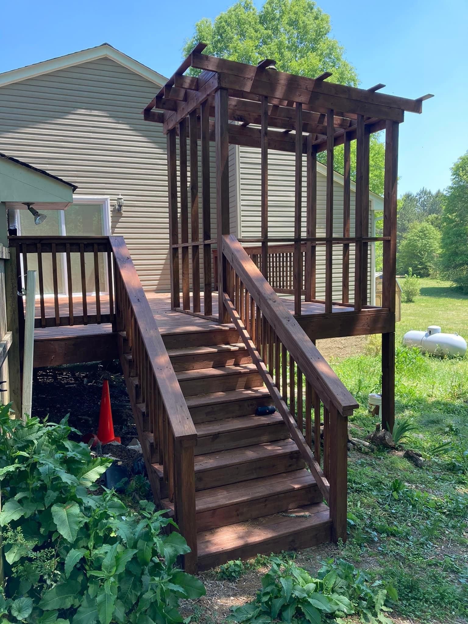 A wooden deck with stairs leading up to it and a pergola.