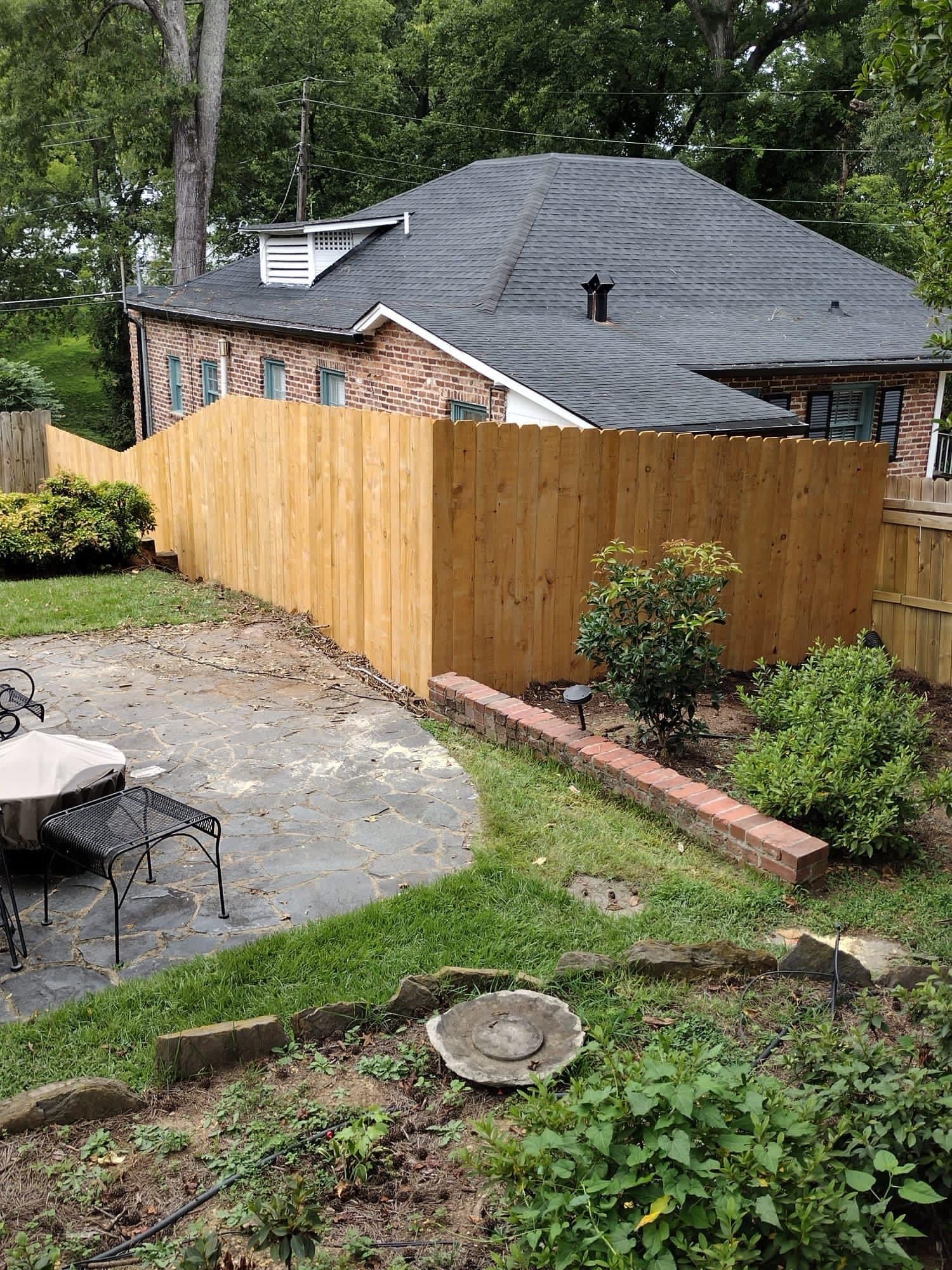 There is a wooden fence in the backyard of a house.
