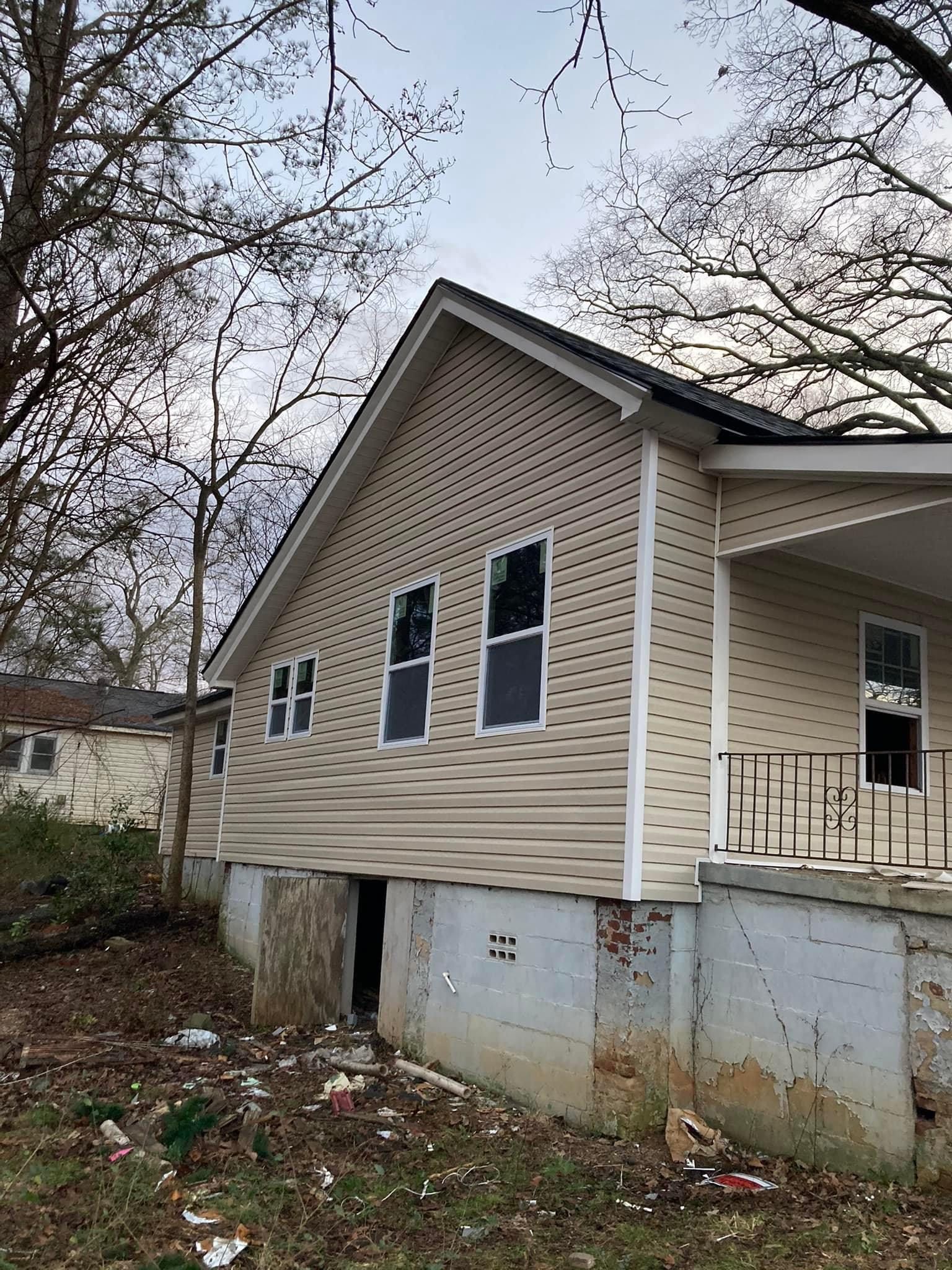 A house with a lot of windows is sitting on top of a dirt field.