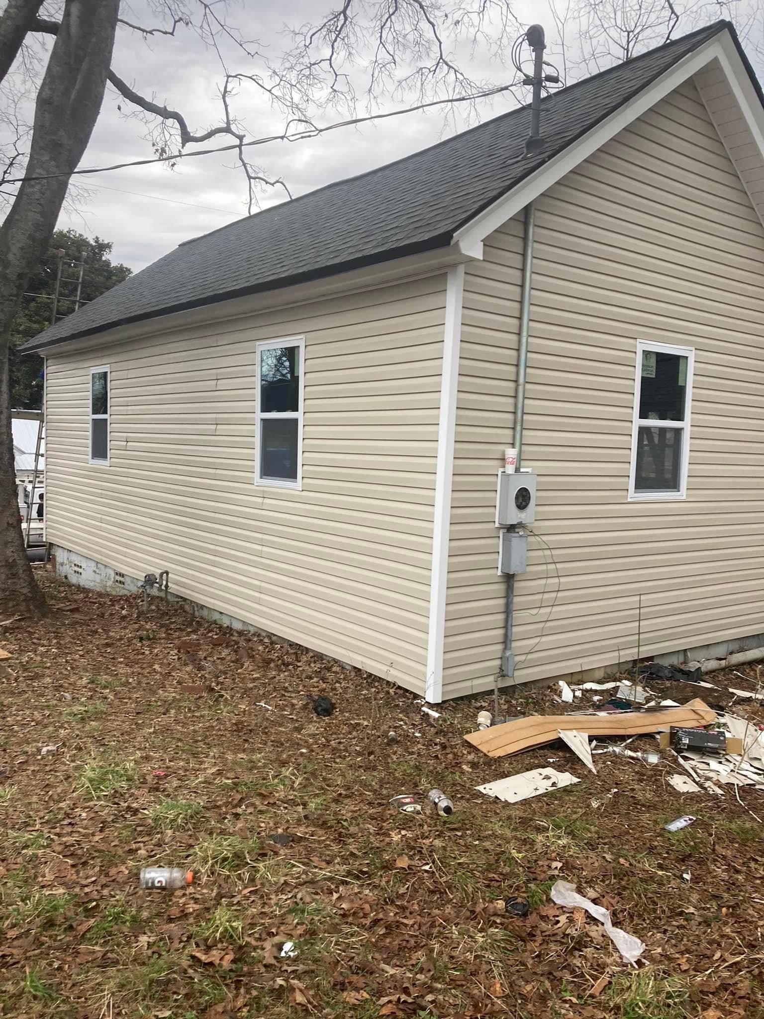 A small house with siding and a roof is sitting on top of a lush green field.
