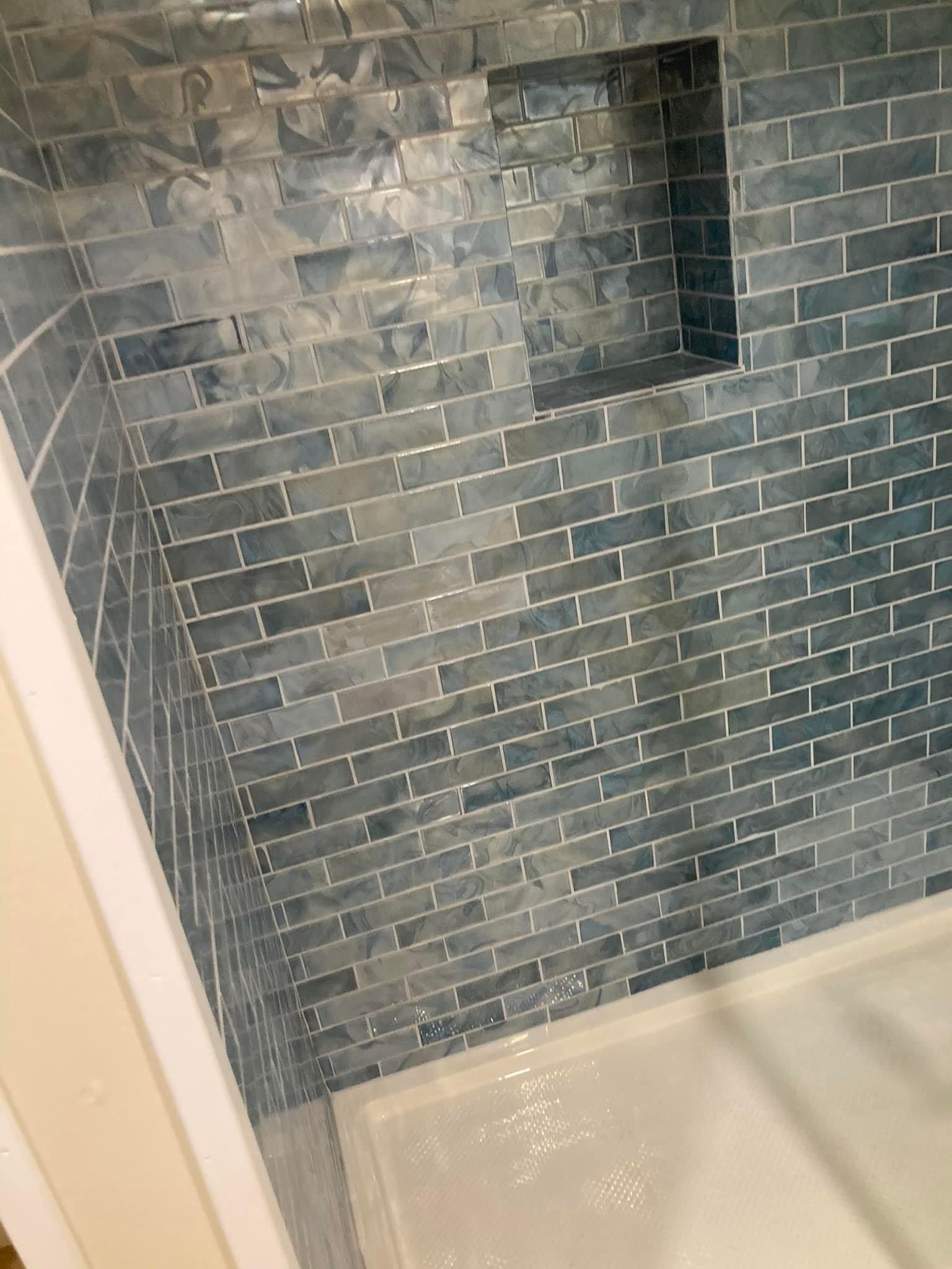 A shower with a brick wall and a niche in the wall.