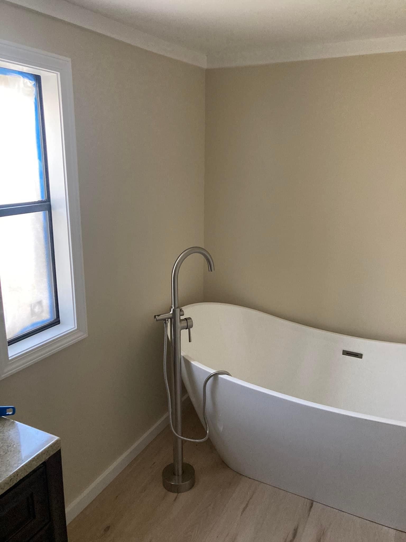 A bathroom with a bathtub and a window.