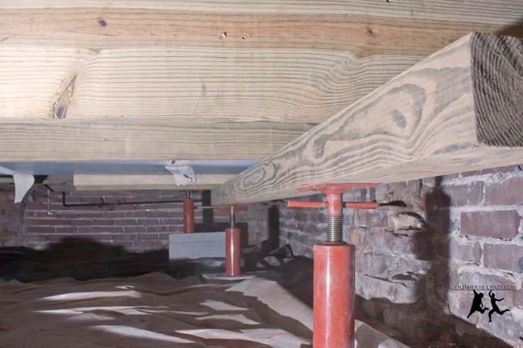 A wooden beam is sitting underneath a brick wall.