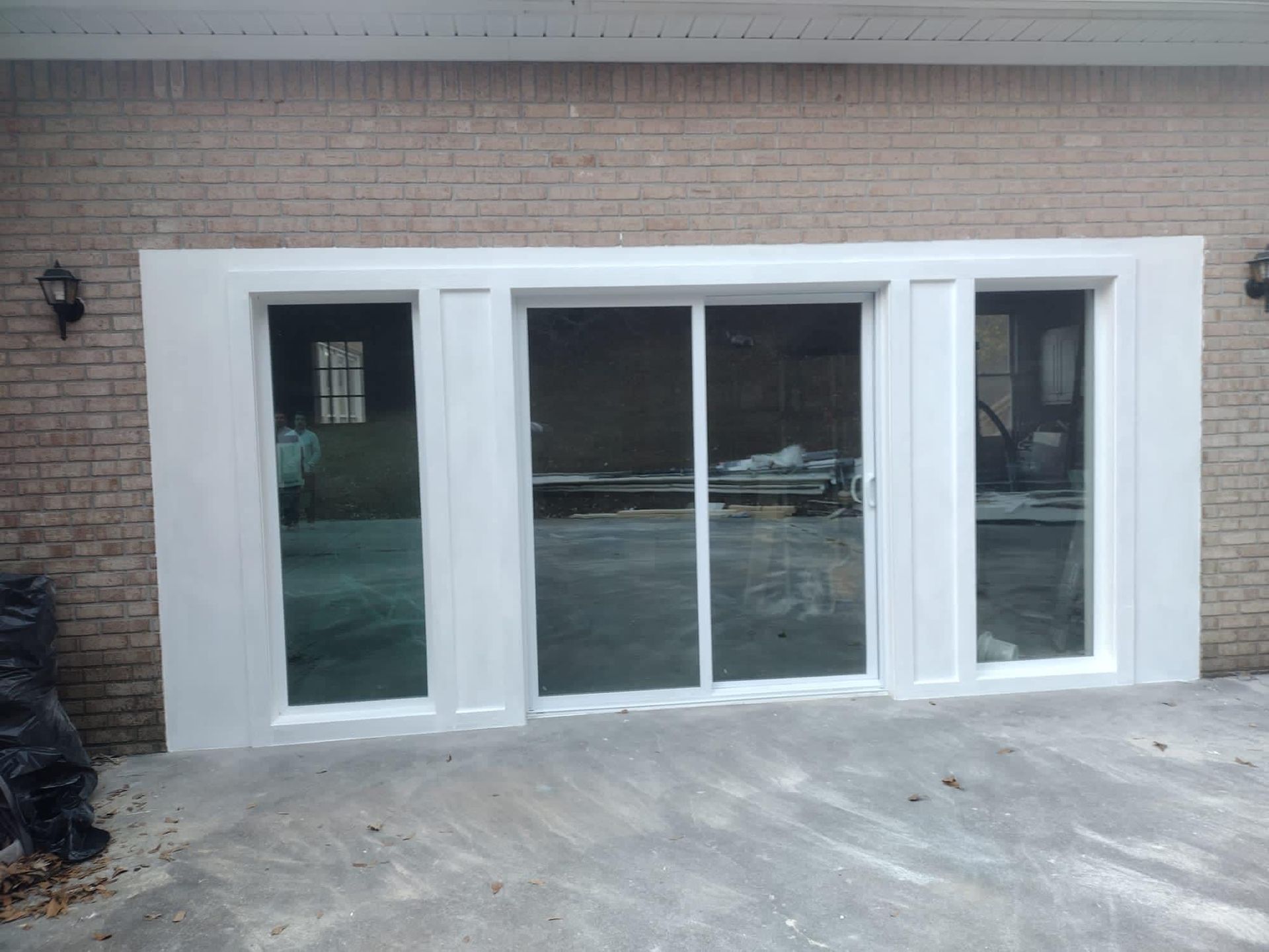 A large white sliding glass door is on the side of a brick building.