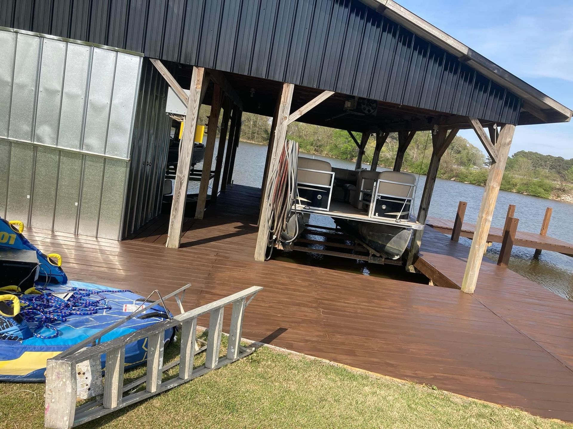 A boat is parked under a covered dock next to a body of water.