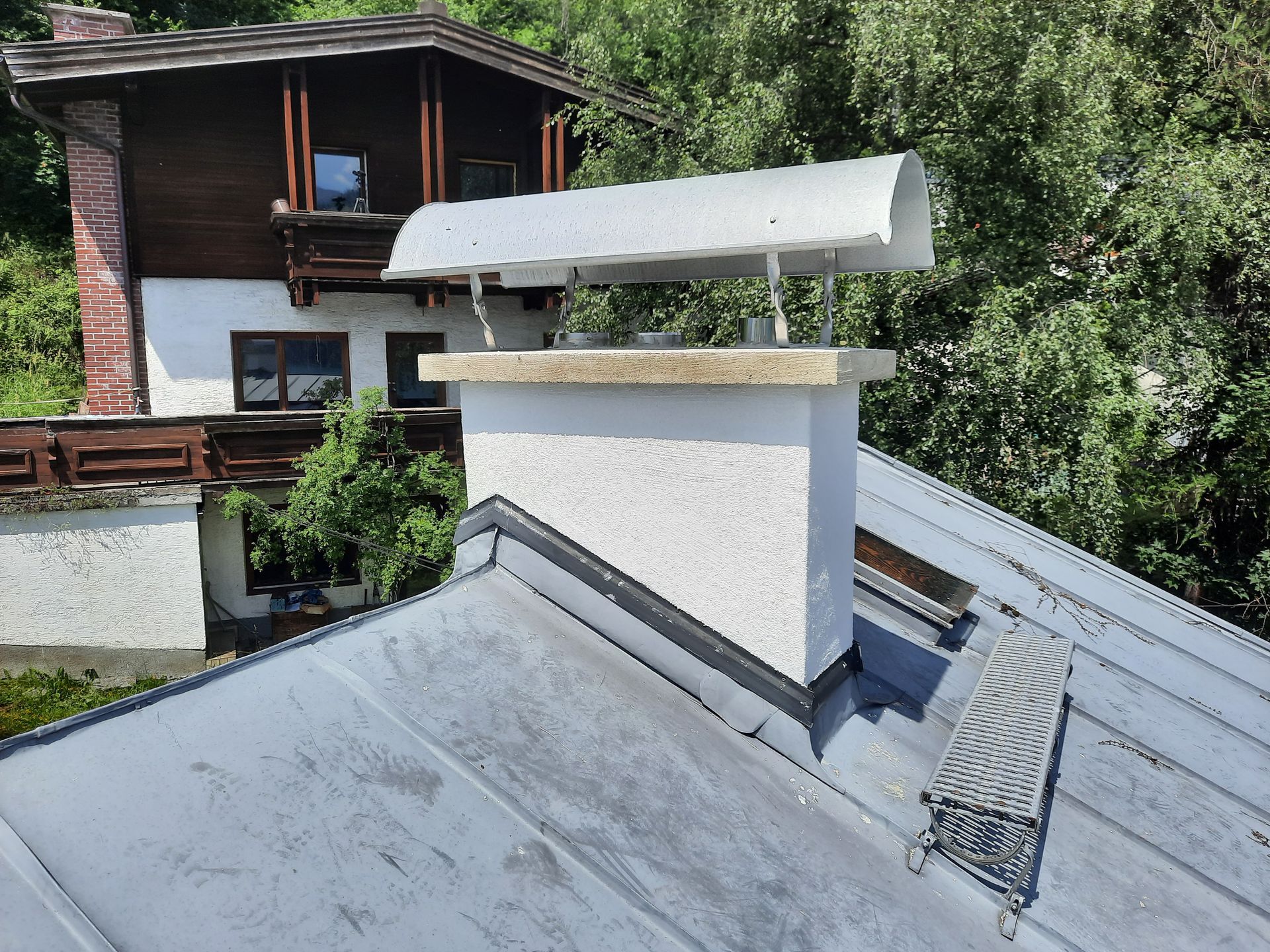 Ein Schornstein auf dem Dach eines Hauses mit Bäumen im Hintergrund