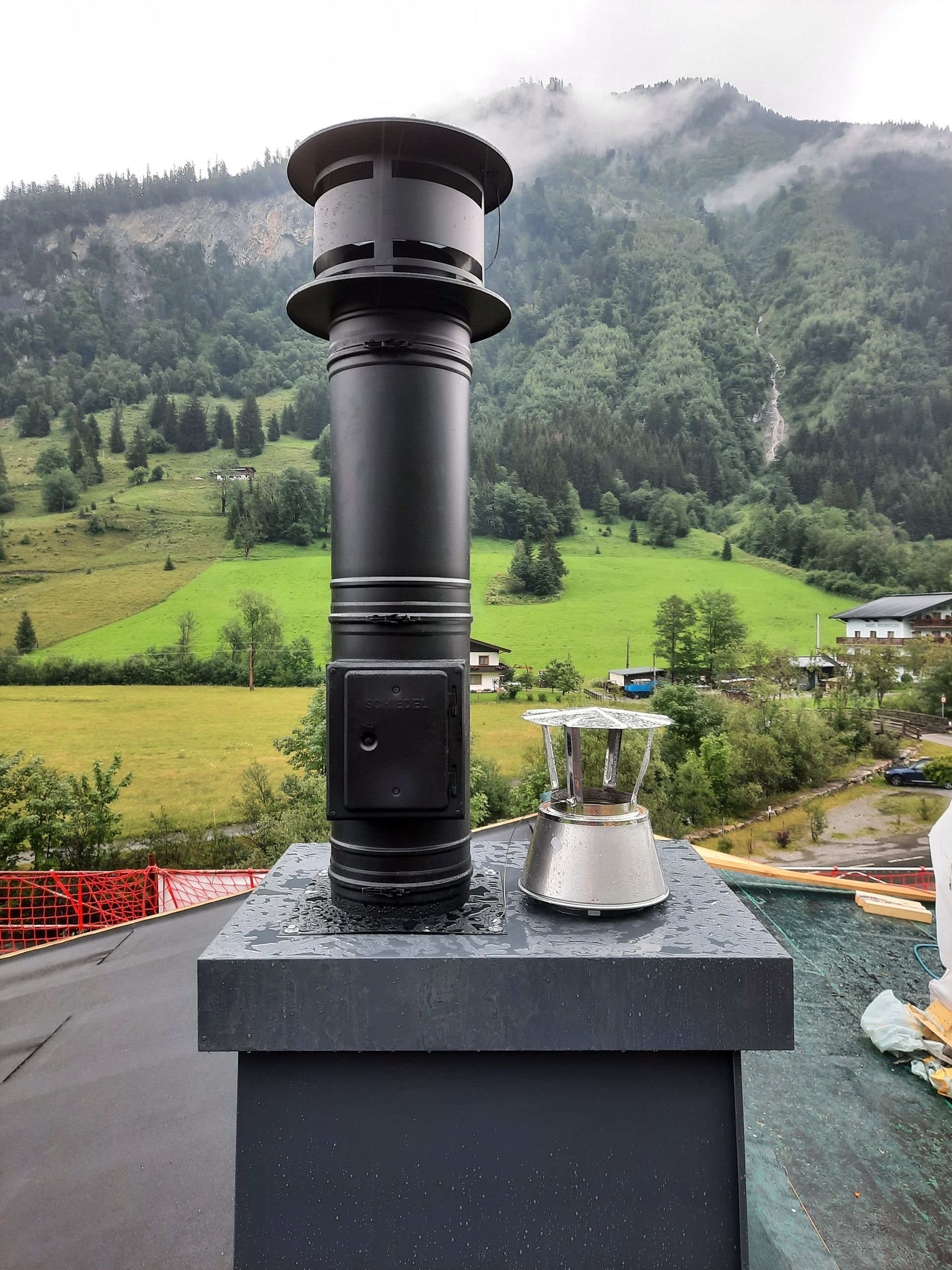 Ein Schornstein auf einem Dach mit Bergen im Hintergrund