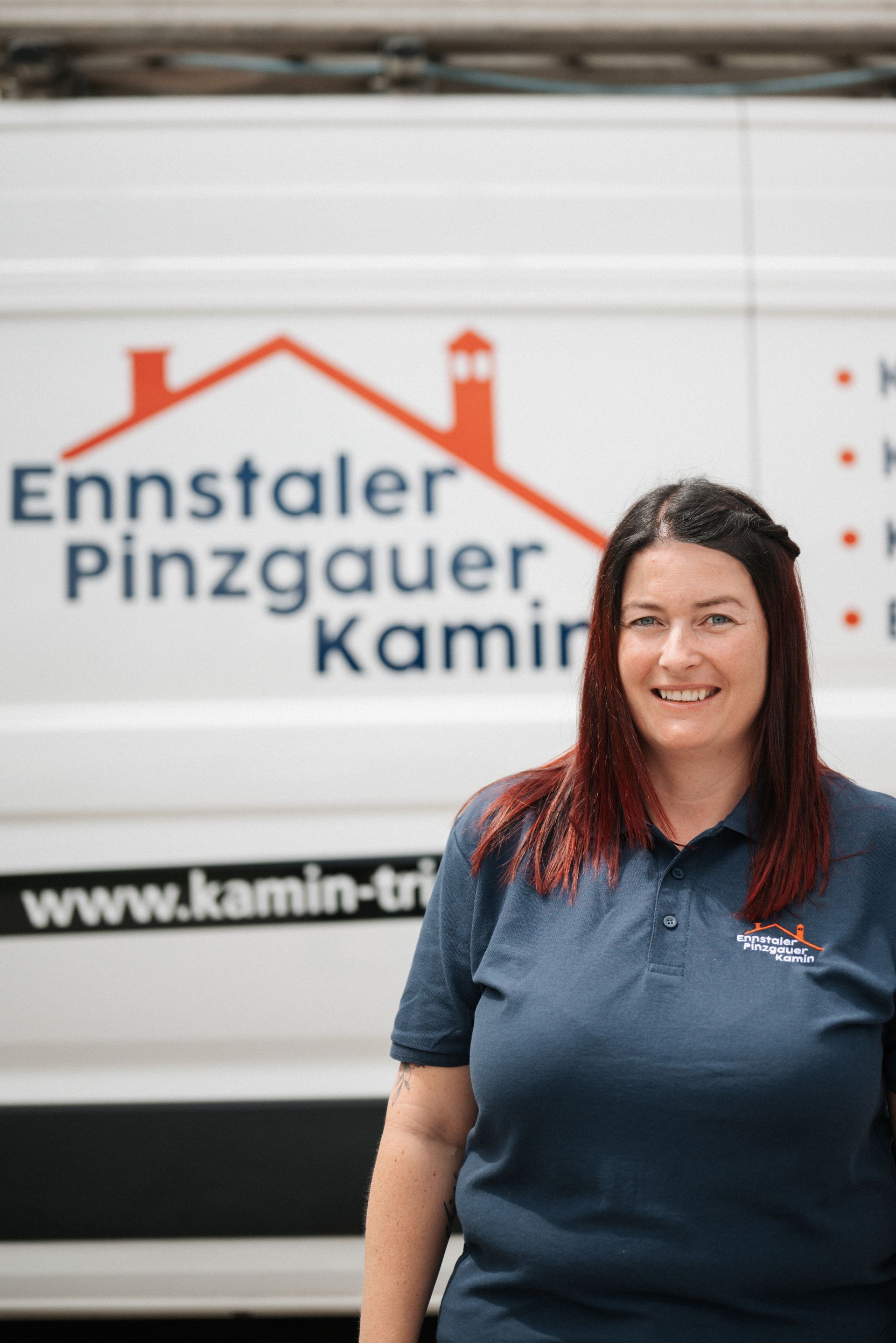 Eine Frau in einem blauen Hemd steht vor einem weißen Lieferwagen.