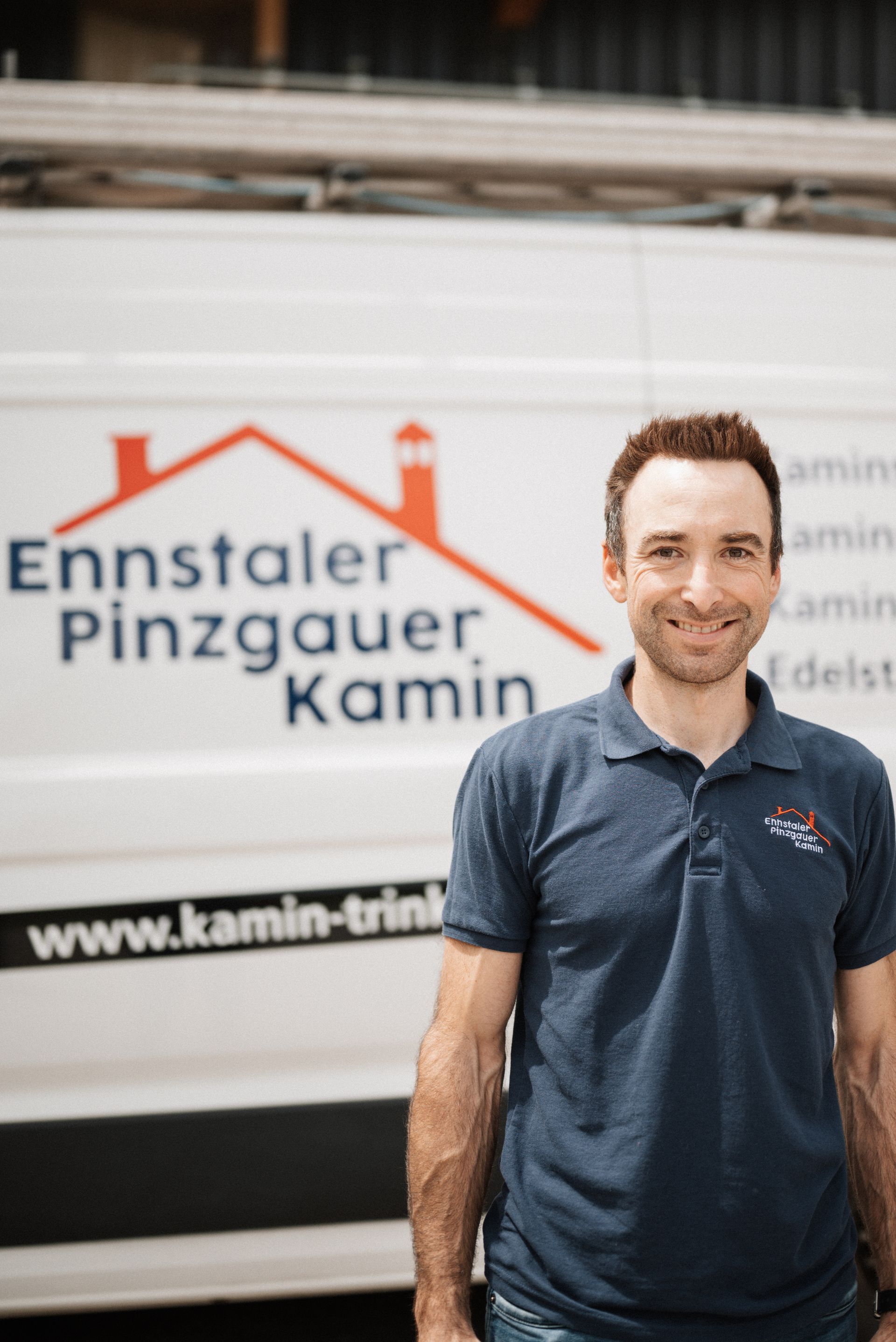 Ein Mann steht vor einem Lieferwagen mit der Aufschrift „Ennstal Pinzgauer Kamin“