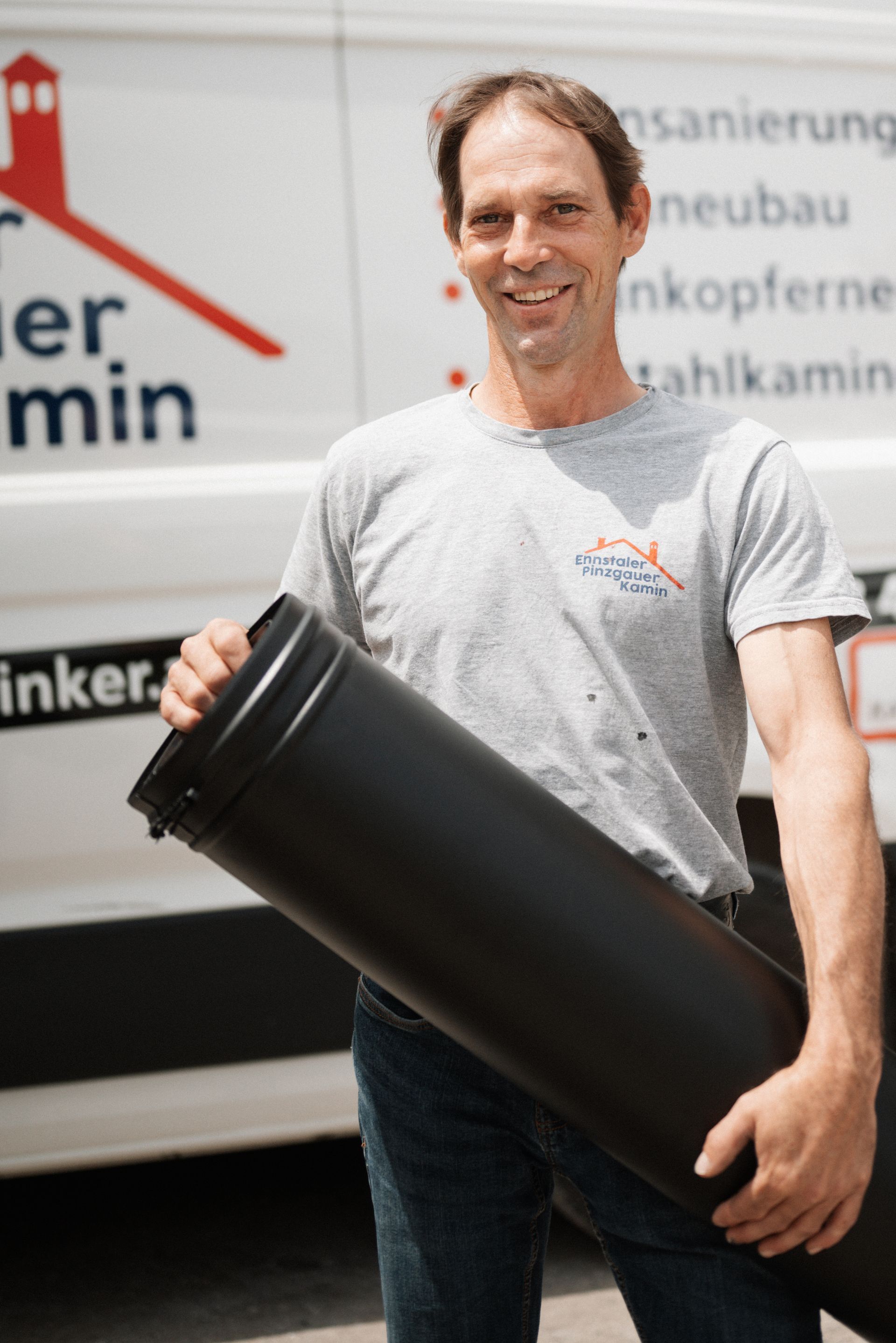 Ein Mann hält eine große schwarze Röhre vor einem Lieferwagen mit der Aufschrift „Keller min“