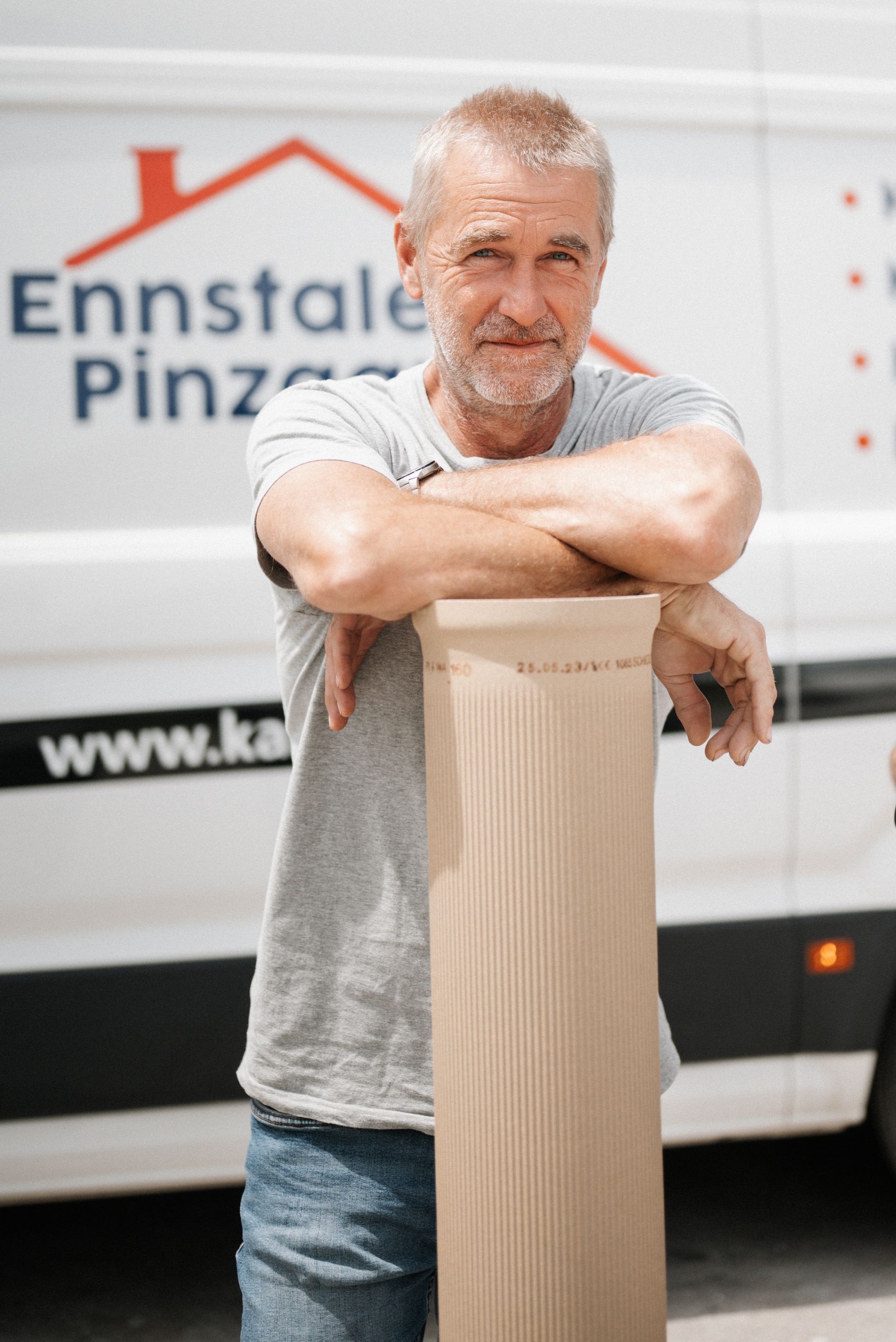 Ein Mann steht mit verschränkten Armen vor einem Lieferwagen.