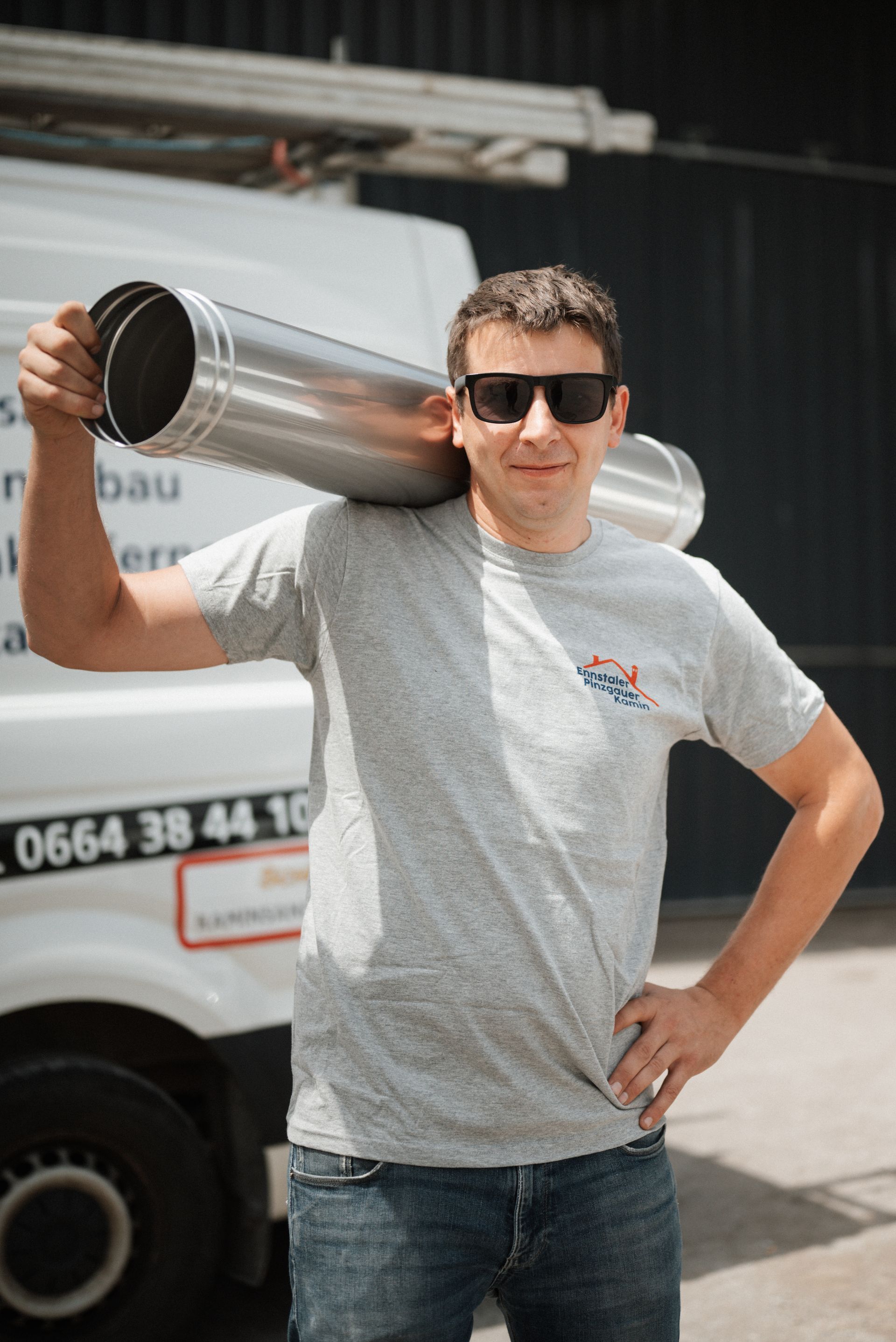 Ein Mann hält vor einem Lieferwagen eine Pfeife auf seiner Schulter.