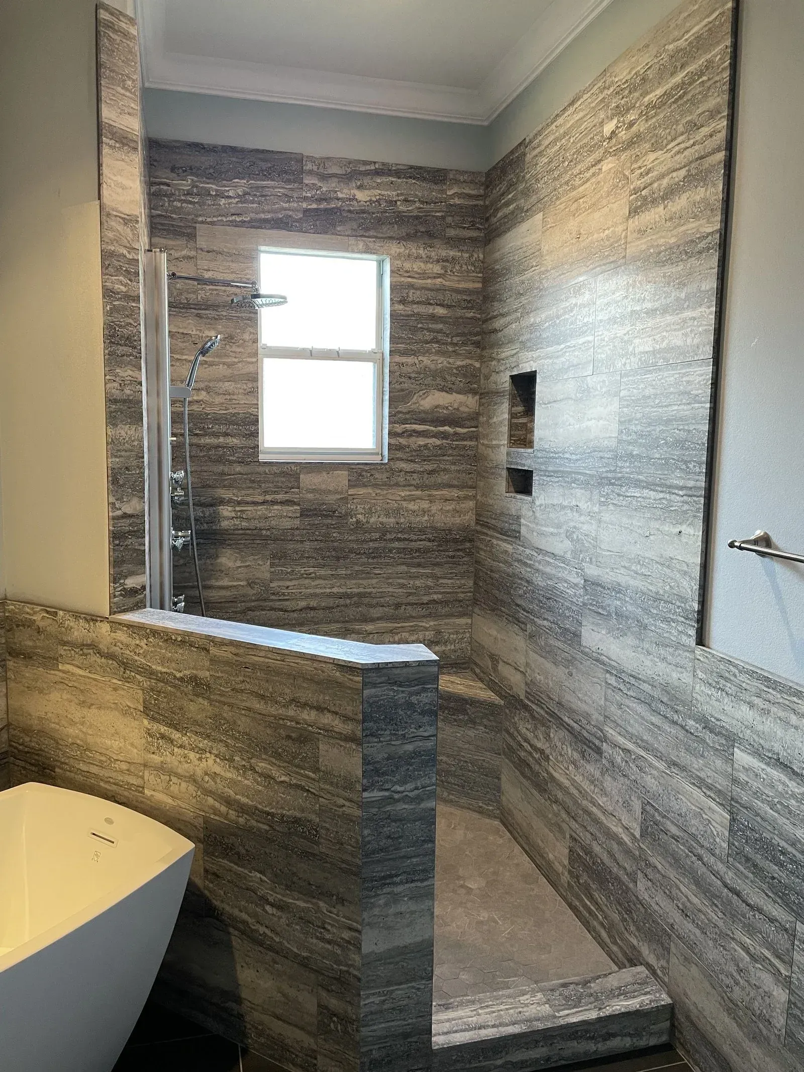 A bathroom with a walk in shower , tub , and window.