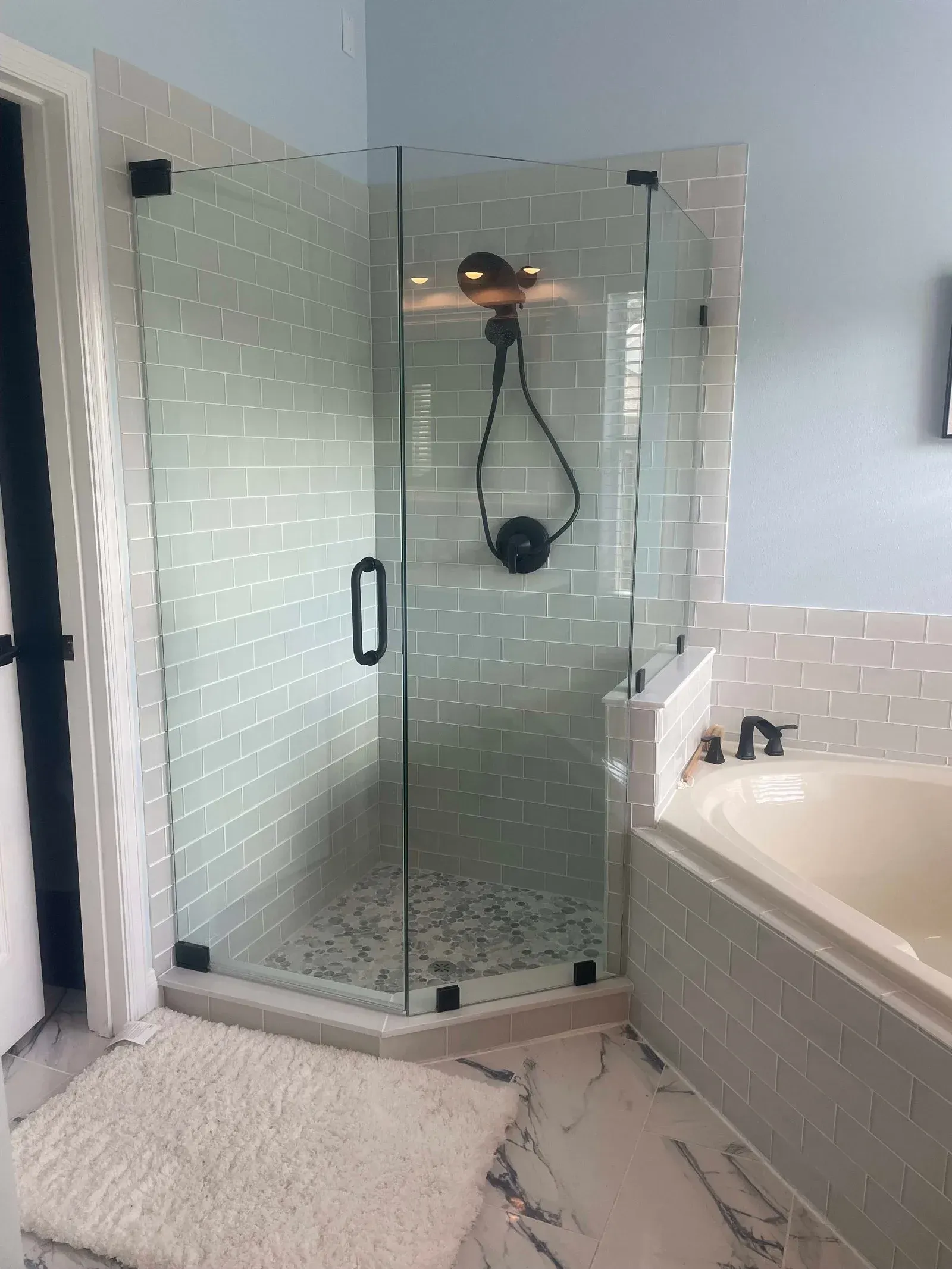 A bathroom with a tub and a shower with a glass door.