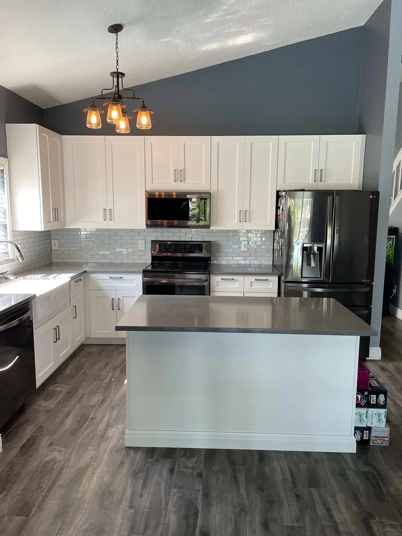 A kitchen with white cabinets , stainless steel appliances , and a large island.