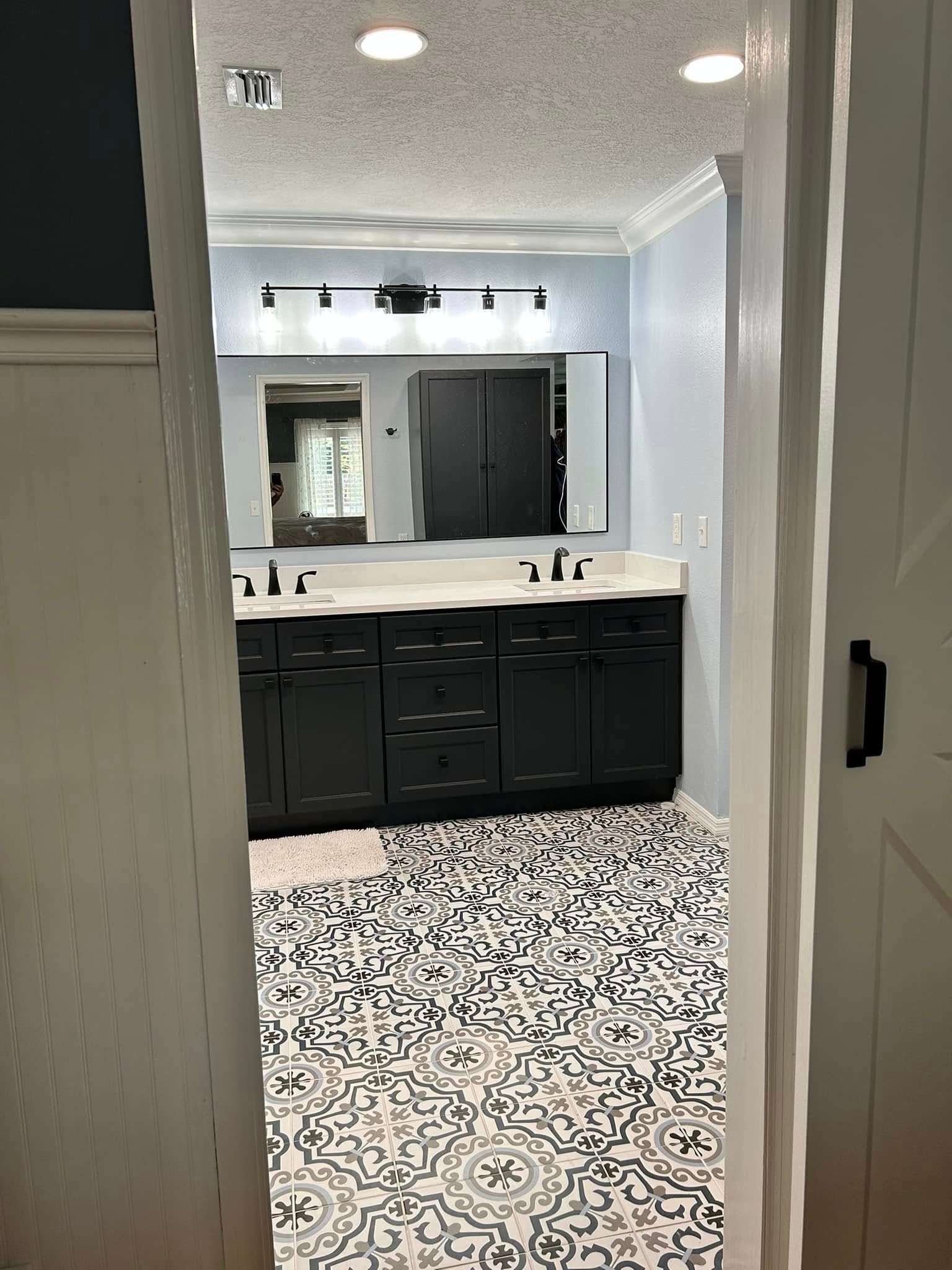 A bathroom with black cabinets and a black and white tile floor.