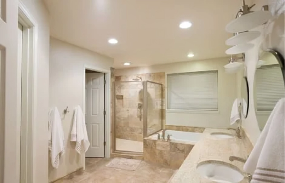 A bathroom with two sinks , a tub , a shower and a mirror.