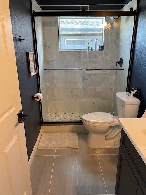 Small bathroom with a navy blue wall and a white toilet. A glass shower is visible.