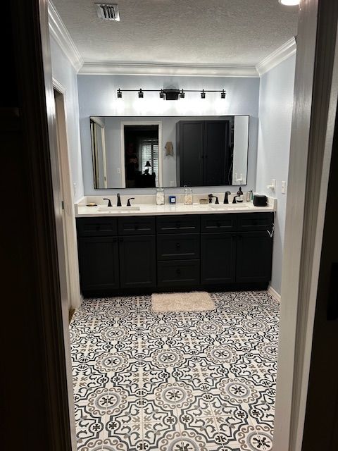 Bathroom with patterned floor, black cabinets, light blue walls, and a large mirror.