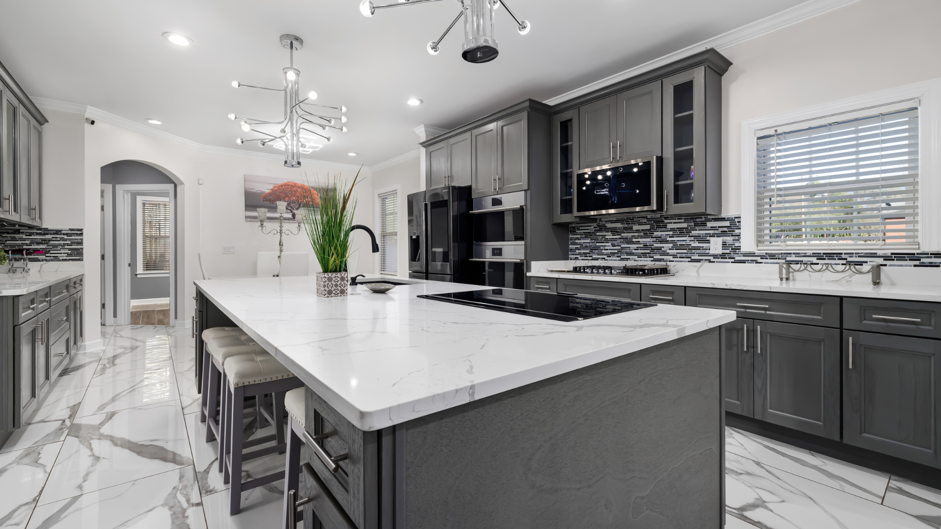 A kitchen with gray cabinets , white counter tops , and a large island.